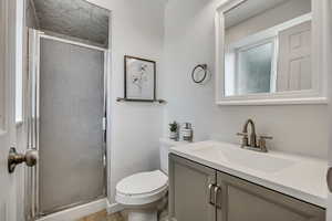 Bathroom featuring vanity, a stall shower, and wood finished floors
