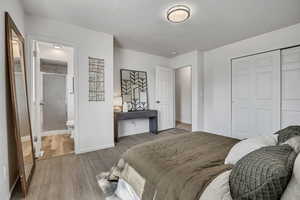 Bedroom featuring wood finished floors, a closet, and ensuite bath