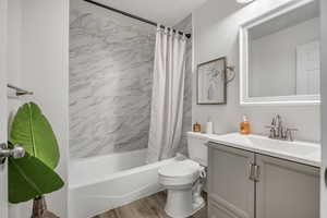 Bathroom with shower / tub combo, vanity, and wood finished floors