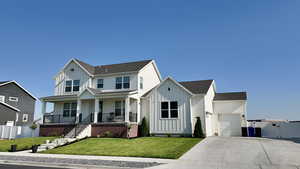 View of front of home with board and batten siding, a porch, a garage, and roof with shingles