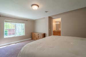 Bedroom with light carpet, a textured ceiling, and ensuite bathroom