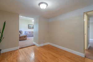 Spare room featuring light wood-style floors, a textured ceiling, and light colored carpet