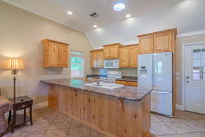 Kitchen featuring crown molding, white appliances, a peninsula, light tile patterned flooring, and light brown cabinets