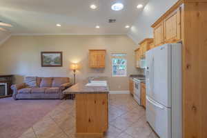 Kitchen featuring light brown cabinetry, crown molding, white appliances, open floor plan, and recessed lighting