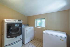 Laundry area featuring separate washer and dryer, a textured ceiling, and light tile patterned floors
