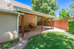Fenced backyard with a ceiling fan and a patio area