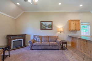 Living area with ornamental molding, a fireplace, recessed lighting, vaulted ceiling, and light tile patterned floors