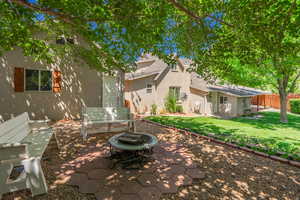 Rear view of house featuring stucco siding, a patio area, an outdoor fire pit, and a shingled roof