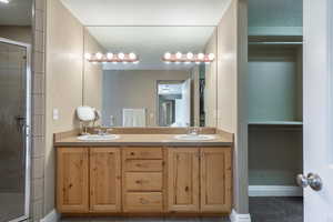 Bathroom with double vanity, a stall shower, a textured ceiling, and tile patterned floors