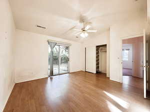 Unfurnished bedroom with vaulted ceiling, access to outside, wood finished floors, multiple windows, and a closet
