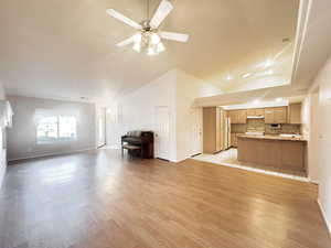 Unfurnished living room featuring vaulted ceiling, light wood finished floors, a ceiling fan, and recessed lighting