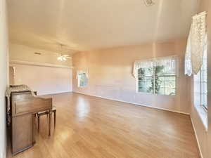 Unfurnished living room with vaulted ceiling, light wood-type flooring, and a ceiling fan