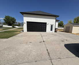 Side entry garage with view of storage shed