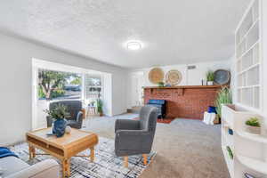 Living room with a wood stove, carpet, and a textured ceiling