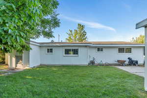 Back of property featuring a yard, a patio area, and roof with shingles
