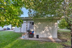 View of side of property with a lawn and a storage unit