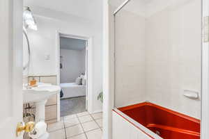 Ensuite bathroom with tile patterned floors and  shower combination