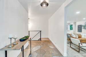 Corridor featuring an upstairs landing, stone tile floors, and recessed lighting