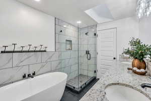 Bathroom with a shower stall, double vanity, a freestanding tub, tile walls, and tile patterned flooring