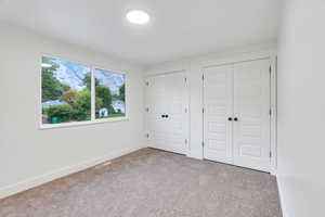 Unfurnished bedroom featuring carpet flooring and multiple closets