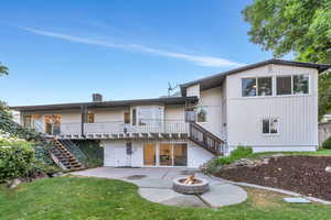 Back of house featuring stairs, an outdoor fire pit, a patio area, and a lawn