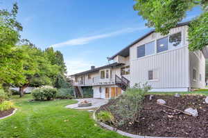 Rear view of property featuring stairs, an outdoor fire pit, a lawn, a deck, and board and batten siding