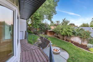 Wooden deck with an outdoor fire pit and a fenced backyard