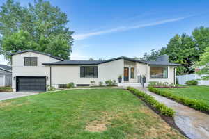 View of front of home with a chimney, concrete driveway, and an attached garage