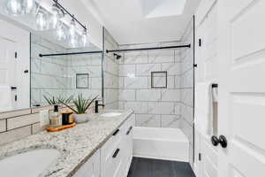 Full bathroom featuring shower / bathtub combination, double vanity, backsplash, and tile patterned flooring