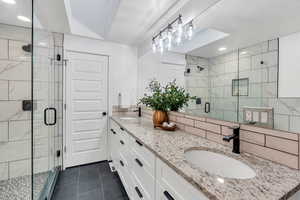 Full bath with recessed lighting, double vanity, a shower stall, tile patterned floors, and tasteful backsplash