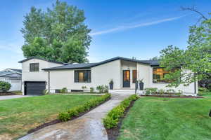 View of front of house featuring a front yard, an attached garage, and concrete driveway