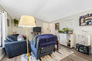 Living area with ornamental molding, wood finished floors, and lofted ceiling