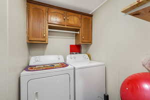 Laundry area with washer and dryer, cabinet space, and a textured ceiling