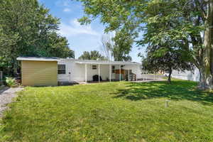 Rear view of property with a lawn and a patio area