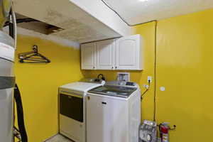 Laundry room with cabinet space, washing machine and clothes dryer, a textured ceiling, and water heater