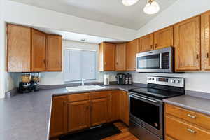 Kitchen with appliances with stainless steel finishes, brown cabinets, and wood finished floors