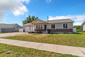 Ranch-style home with an attached garage, brick siding, driveway, and a front yard