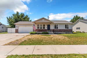 Ranch-style home featuring an attached garage, a front yard, concrete driveway, and brick siding