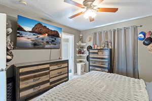Bedroom with a textured ceiling, carpet, and a ceiling fan