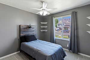 Carpeted bedroom with a textured ceiling, ceiling fan, and a mountain view