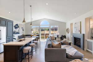Living area with lofted ceiling, light wood finished floors, recessed lighting, and a glass covered fireplace