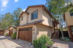 View of front facade with stucco siding, a garage, and driveway