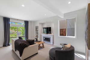 Living area featuring light carpet, beamed ceiling, a premium fireplace, and recessed lighting