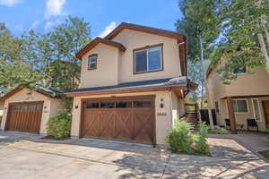 View of front of property featuring a garage, stucco siding, stairway, and concrete driveway