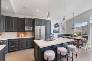 Kitchen featuring vaulted ceiling, light wood finished floors, light countertops, tasteful backsplash, and appliances with stainless steel finishes