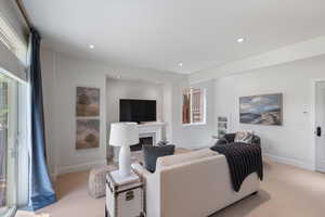 Living room with light colored carpet, plenty of natural light, a fireplace, and recessed lighting