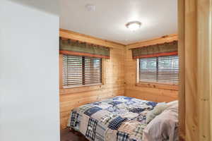 Bedroom with multiple windows and wood walls