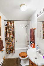 Full bathroom featuring a baseboard heating unit, shower / bath combo, and vanity