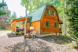 View of side of property with a deck, a metal roof, and a gambrel roof