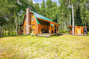 Rear view of house featuring a yard, a metal roof, a chimney, and an outbuilding